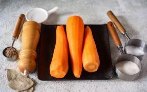 Paruoškite ingredientus. Nulupkite ir nuplaukite morkas. Sterilizuokite konservavimo stiklainius ir dangtelius patogiu būdu.