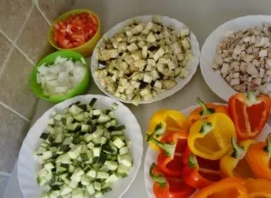 Paruoškime daržoves. Pirmiausia jas nuplaukite. Paprikas perpjaukite per pusę ir išimkite sėklas. Likusias daržoves, išskyrus česnaką, su...