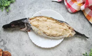 Žuvį šiek tiek pasūdykite iš vidaus, patepkite citrinos sultimis ir įdėkite paruoštą faršą, tolygiai paskirstydami.