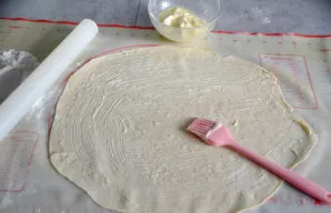 Iškočiokite vieną tešlos gabalą į didelį ploną lakštą. Jei tešla limpa, pabarstykite stalą miltais. Patepkite tešlą suminkštintu sviestu ...