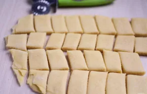 Dabar sulenktą tešlą supjaustykite nedideliais stačiakampiais - tai būsimo sausainio ruošiniai.