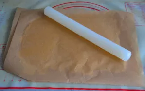 Iškočiokite tešlą pagal formos dydį. Tai patogu daryti tarp dviejų kepimo popieriaus lapų arba pabarstant stalą ir kočėlą miltais.