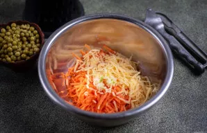 Dideliame dubenyje sumaišykite tarkuotą morką, pusę tarkuoto sūrio, įspauskite 2 nuluptas česnako skilteles per česnako spaudiklį.