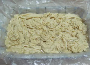 Antrąją tešlos dalį praleiskite per mėsmalę ir dalimis sudėkite ant įdaro.