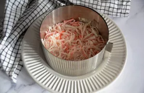 Antru sluoksniu dėkite smulkintas krabų lazdelės.