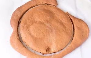 Iškart karštą, kol minkšta, korą apipjaukite į apskritimą, mano apskritimas – 16 cm skersmens. Likusius kraštus išsaugokite torto apibars...