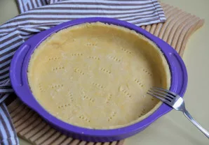 Išklokite tešlą formoje, suformuokite bortelius, dugną subadykite šakute.