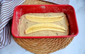 Banano gabalėlius perpjaukite per pusę ir dėkite ant tešlos viršaus.