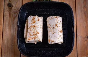 Suvyniokite tortilijas, užlenkdami kraštus, ir sudėkite į sausą keptuvę. Kepinkite buritus ant vidutinės ugnies po 3-4 minutes iš abiejų ...