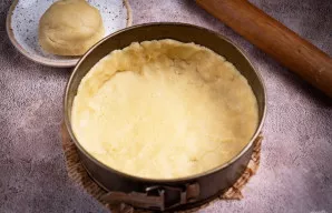 Gerai atvėsintą tešlą padalykite į dvi nelygias dalis. Didesnę dalį iškočiokite į apskritimą ir įklokite į kepimo formą (iš anksto išklok...