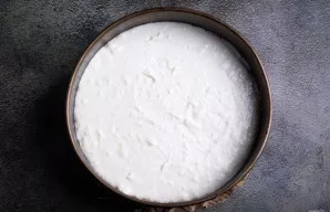 Iš šaldytuvo išimkite formą su pagrindu ir atsargiai užpilkite varškės sluoksnį. Vėl padėkite į šaldytuvą 1 valandai sustingti.