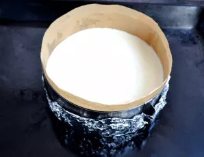 Supilkite sūrio masę į kepimo formą. Orkaitėje nustatykite 120 °C. Įdėkite pyraga kepti.