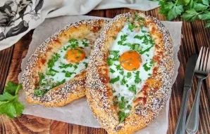 Khachapuri grąžinkite atgal į orkaitę ir kepkite, kol baltymai išsipūs. Patiekdami, jei norite, į kiekvieną valtį įdėkite gabalėlį sviest...