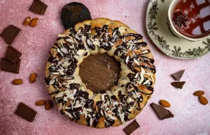 Atvėsusį keksą papuoškite tirpintu šokoladu ir pabarstykite smulkintais migdolais.