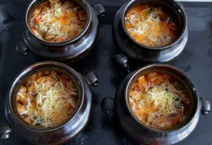 Po 1-1 val. 15 min. išimkite puodelius, nuimkite dangtelius, pabarstykite tarkuotu sūriu ir kepkite dar 15-20 minučių.