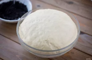 Patogumo dėlei padalykite tešlą į dvi dalis ir kiekvieną iškočiokite ant darbo paviršiaus į stačiakampį lakštą.