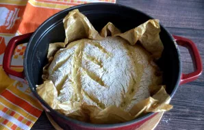 Atsargiai perkelkite duoną į karštą puodą laikydami popieriaus kampučius, uždenkite dangčiu ir kepkite 30 minučių 230 laipsnių temperatūr...