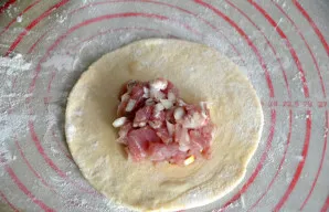 Įjunkite orkaitę ir įkaitinkite ją „viršus-apačia“ režimu iki 180 laipsnių. Iškočiokite tešlos gabalėlį į lakštą, į centrą dėkite įdarą.