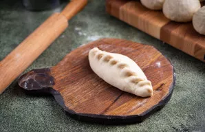 Užlenkite tešlos kraštus patogiu būdu, formuodami pyragėlio formą.