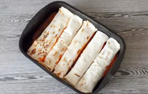 Formos dugne supilkite 1/4 paruošto padažo. Sudėkite paruoštus ritinėlius su įdaru.