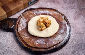 Rutuliuką suplokite rankomis į paplotėlį ir į vidurį dėkite 2 arbat. šaukštelius atvėsusio obuolių įdaro.