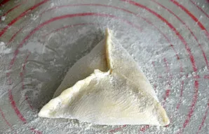 Suformuokite trikampį pyragėlį - samsą, kruopščiai užspauskite kraštus, ypač centre, kad kepant neišbėgtų sultys. Dėkite ant kepimo skard...