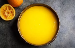 Iš šaldytuvo išimkite formą ir atsargiai užpilkite apelsinų sluoksnį ant varškės. Vėl padėkite į šaldytuvą 1 valandai.