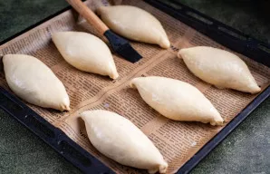 Visus pyragėlių ruošinius dėkite siūlu žemyn ant kepimo skardos, išklotos kepimo popieriumi. Kiekvieną pyragėlį patepkite plakto trynio i...