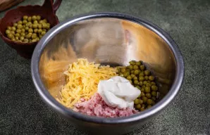 Dideliame dubenyje sumaišykite tarkuotą kumpį, likusią sūrio dalį, konservuotus žirnelius, įdėkite 2 valg. šaukštus majonezo.