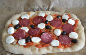 Ant karšto papločio uždėkite pomidorų padažą, mocarelą, alyvuoges arba juodąsias alyvuoges, saliamio griežinėlius. Kepkite dar apie 5 min...