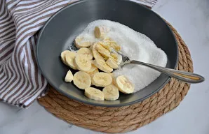 Šakute arba kitu būdu sutrinkite vieną bananą su cukrumi iki vientisos masės.