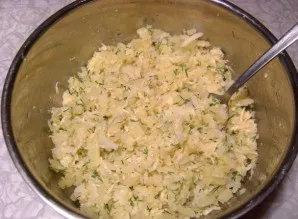 Bulves išvirkite pasūdytame vandenyje, atvėsinkite ir sutarkuokite. Įdėkite tarkuoto sūrio ir smulkintų žalumynų, išmaišykite.