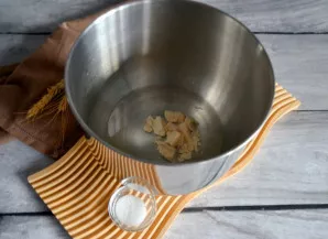 Į tešlos maišymo dubenį supilkite šiltą vandenį, įberkite mielių, cukraus ir išmaišykite. Palikite 10 minučių mielėms aktyvuotis.