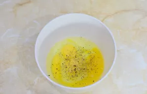 Dubenyje sumaišykite kiaušinius su druska ir prieskoniais.