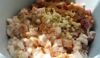 Smulkiai supjaustykite česnaką, sudėkite į mėsą, įberkite druskos, pipirų ir pabarstykite prieskoniais.