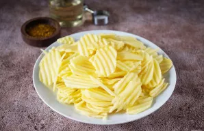 Supjaustykite bulves plonais griežinėliais naudojant virtuvinį kombainą su pjaustymo priedu arba mandolinę. Jei tokių įrenginių neturite,...