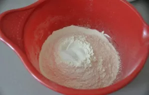 Į dubenį tešlai minkyti persijokite miltus, įberkite druskos, cukraus ir išmaišykite.