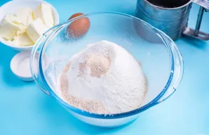 Į didelį dubenį persijokite visus miltus ir suberkite greito veikimo mieles. Išmaišykite.