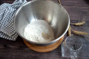 Sumaišykite dubenyje abu miltų tipus, suberkite sausas mieles ir išmaišykite.