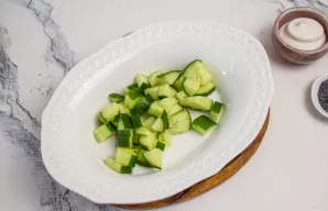 Šviežią agurką nuplaukite ir nusausinkite. Supjaustykite nedideliais kubeliais ir sudėkite į salotinę.