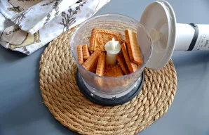 Sutrinkite sausainius iki trupinių blenderiu arba sudėkite į maišelį ir sutrupinkite kočėlu.