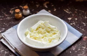 Perkelkite varškę į dubenį ir šiek tiek sutrinkite šakute.