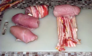 Susukame į vyniotinį. Tada ploną šoninės juostelę apvyniojame aplink vyniotinį. Smeigiame su dantų krapštukais. Sudedame į kepimo indą.