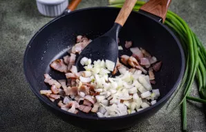 Įdėkite smulkintą svogūną. Kepkite kartu, maišydami mentele, kol svogūnas suminkštės ir taps švelniai auksinis.