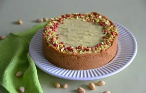 Užtepkite pistacijų kremą ant pyrago paviršiaus, suformuokite gražias bangeles, apibarstykite smulkintomis pistacijomis ir liofilizuotomi...