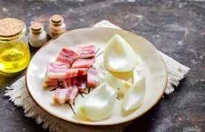 Lašinius supjaustykite atsitiktiniais gabalėliais, taip pat nulupkite svogūną.