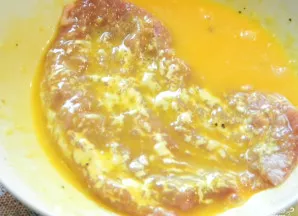 Kiaušinius išplakite su pienu ir panardinkite į šią masę šnicelį.