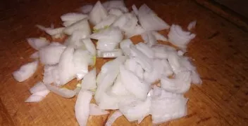 Kai kiaulienos lašiniai ištirps, sudėkite bulves. Smulkiai supjaustykite svogūną ir sudėkite į keptuvę.