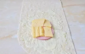 Ant pita duonos sudėkite pjaustytą kumpį ir sūrį.