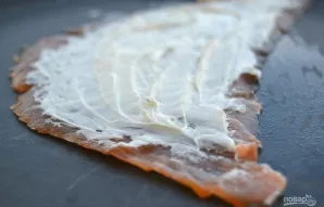 Ploną žuvies riekelę aptepkite kreminiu sūriu, palikdami kraštus neapteptus.